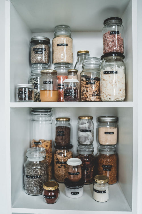 Food storage jars lined up and labelled on a shelf