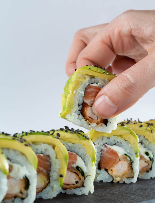 Avocado maki roll held in the hand, a vegetarian sushi option
